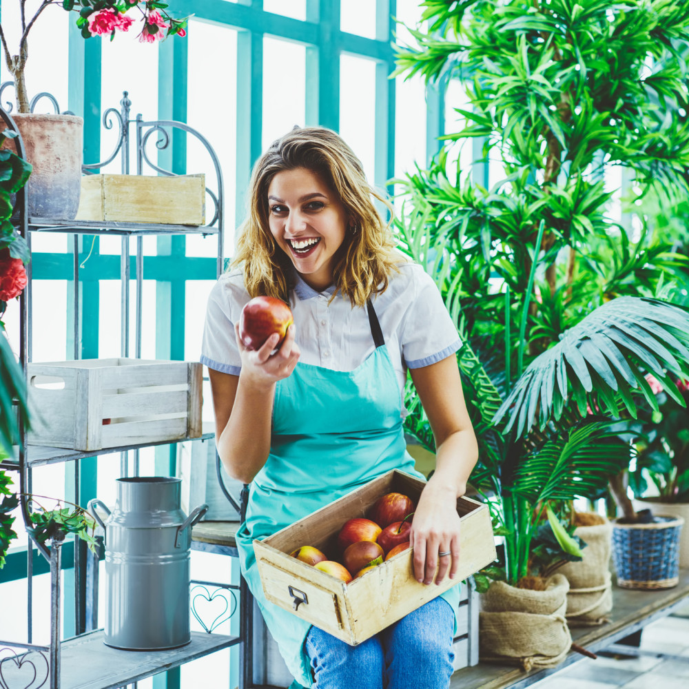 Foto van jonge onderneemster met een kist met appels