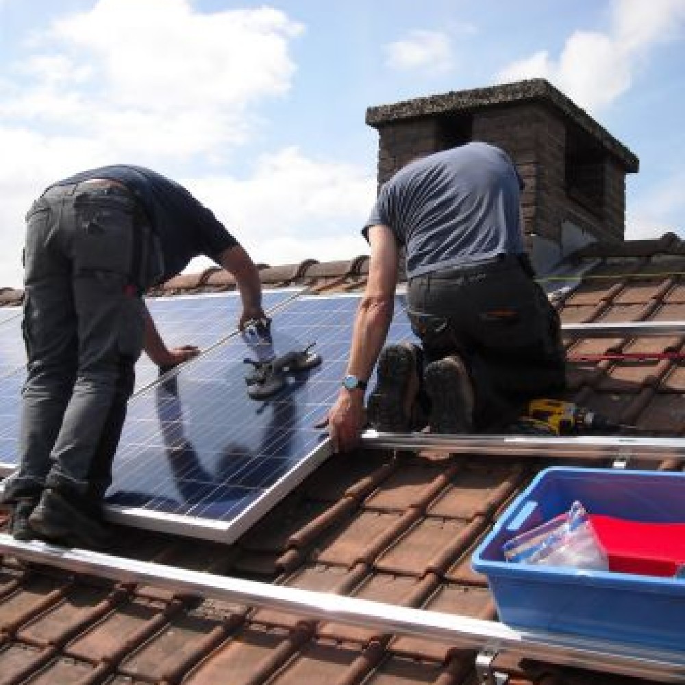 Twee mannen installeren zonnepanelen op het dak van een huis