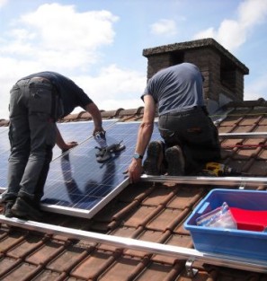 Twee mannen installeren zonnepanelen op het dak van een huis