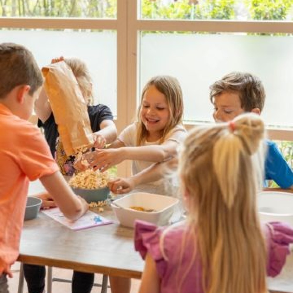 Vijf kinderen doen een interafctief groentenspel aan tafel