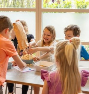 Vijf kinderen doen een interafctief groentenspel aan tafel