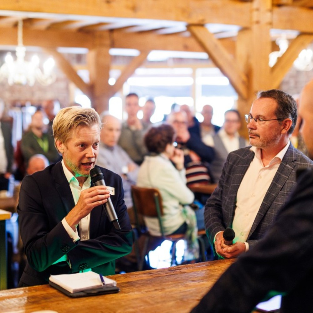  Mark Roscam-Abbing (links) en Mario Jacobs (rechts) met elkaar in gesprek aan een tafel 