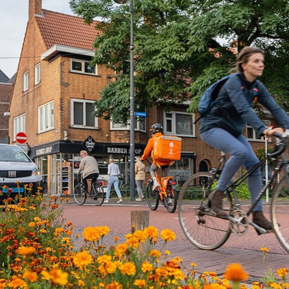 Foto van fietsende mensen op een dorpsplein met een kapper
