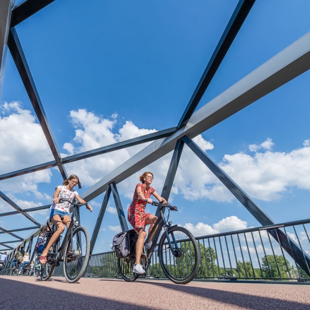 Moeder en dochter fietsen achter elkaar op een fietsbrug