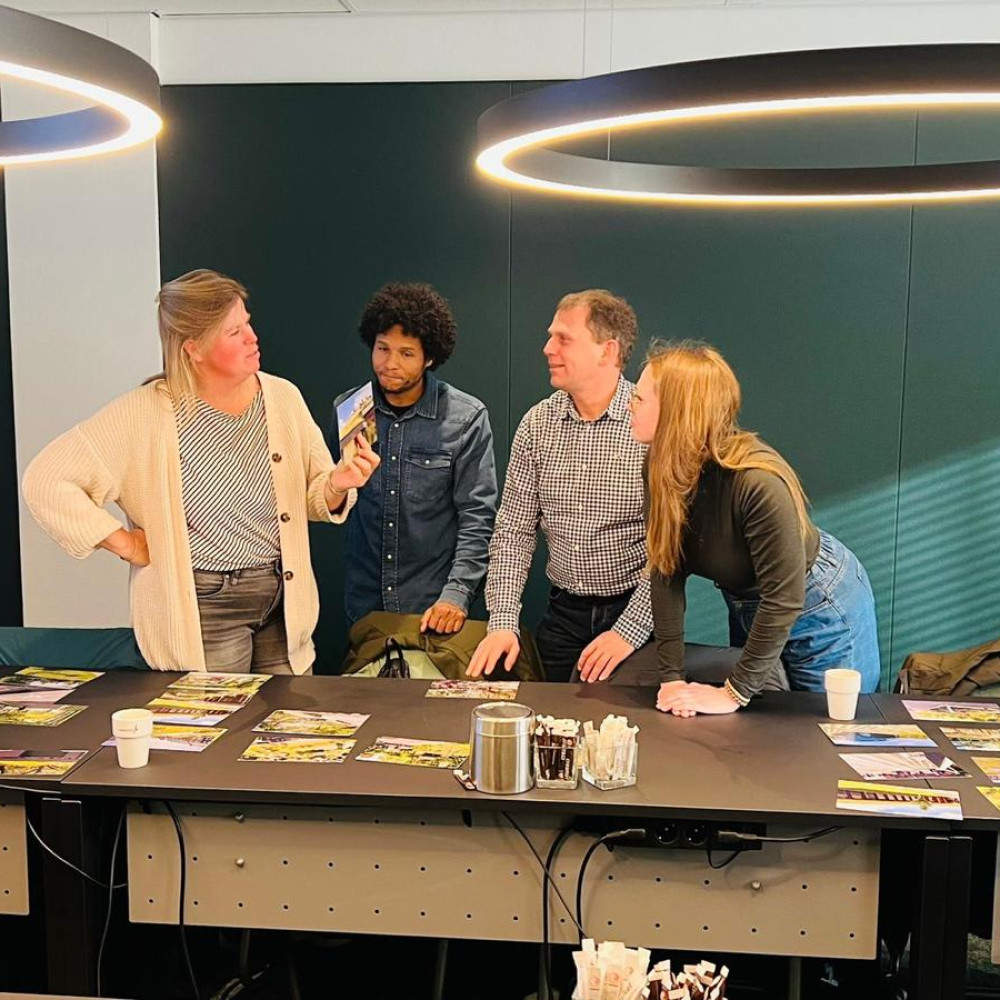 Vier deelnemers aan de wokshop met elkaar in gesprek, staande bij ene tafel