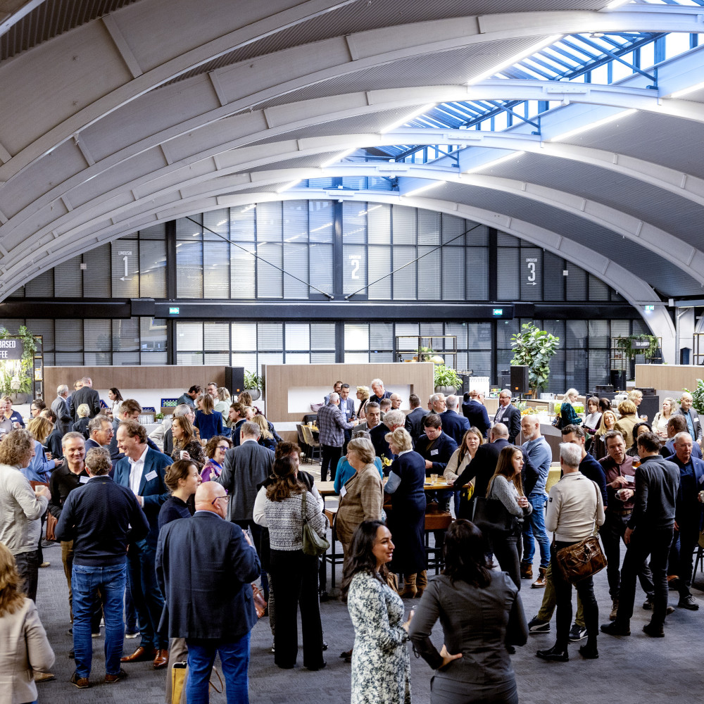Overzichtsfoto van deelnemers aan het slotevent in een grote hal