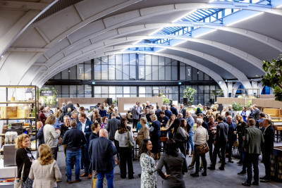 Overzichtsfoto van deelnemers aan het slotevent in een grote hal