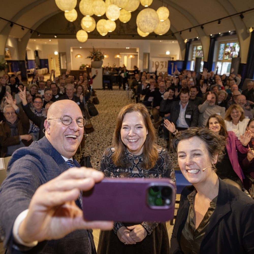 Drie bestuurders van regio, rijk en provincie nemen een selfie met de deelnemers van het sloteven op de achtergrond