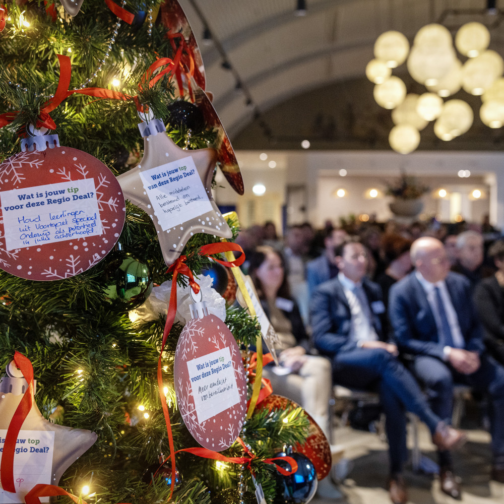 Close up van kerstboom met kerstballen waar een tekst op is geschreven