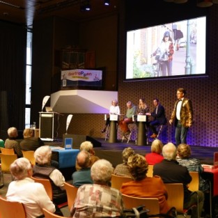 Paneldiscussie met verkeerspartijen op een podium in een zaal met deelnemers aan de quiz 