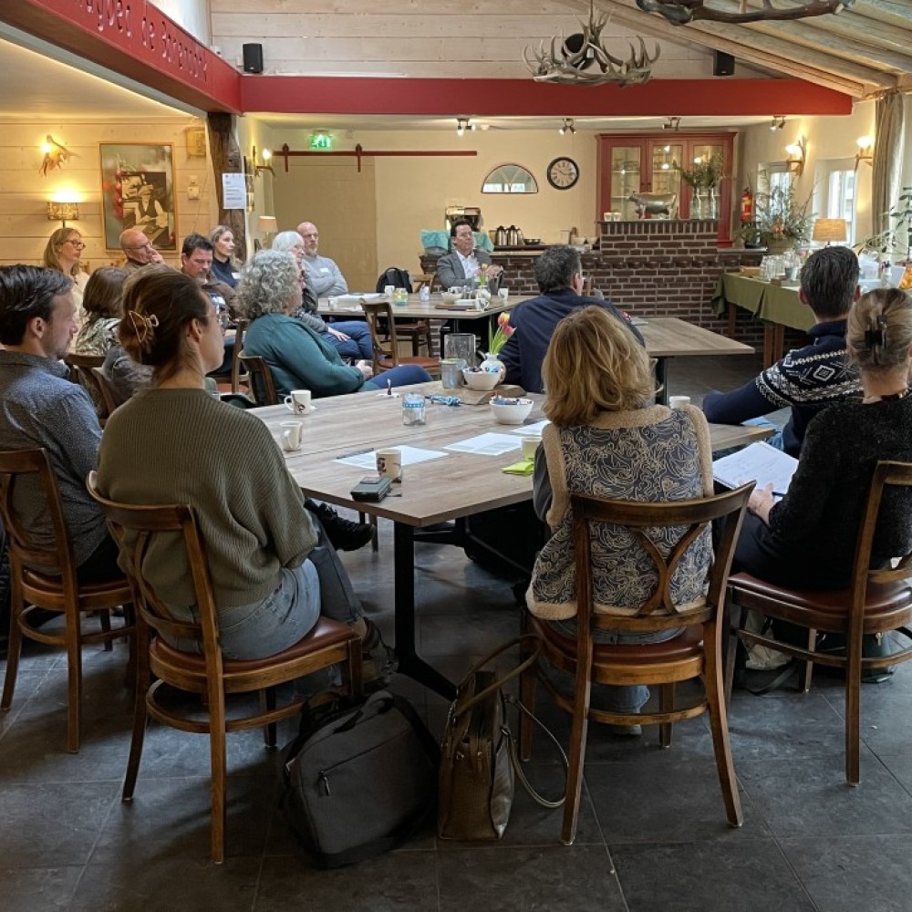 Deelnemers aan de werksessie zitten aan verschillende tafels