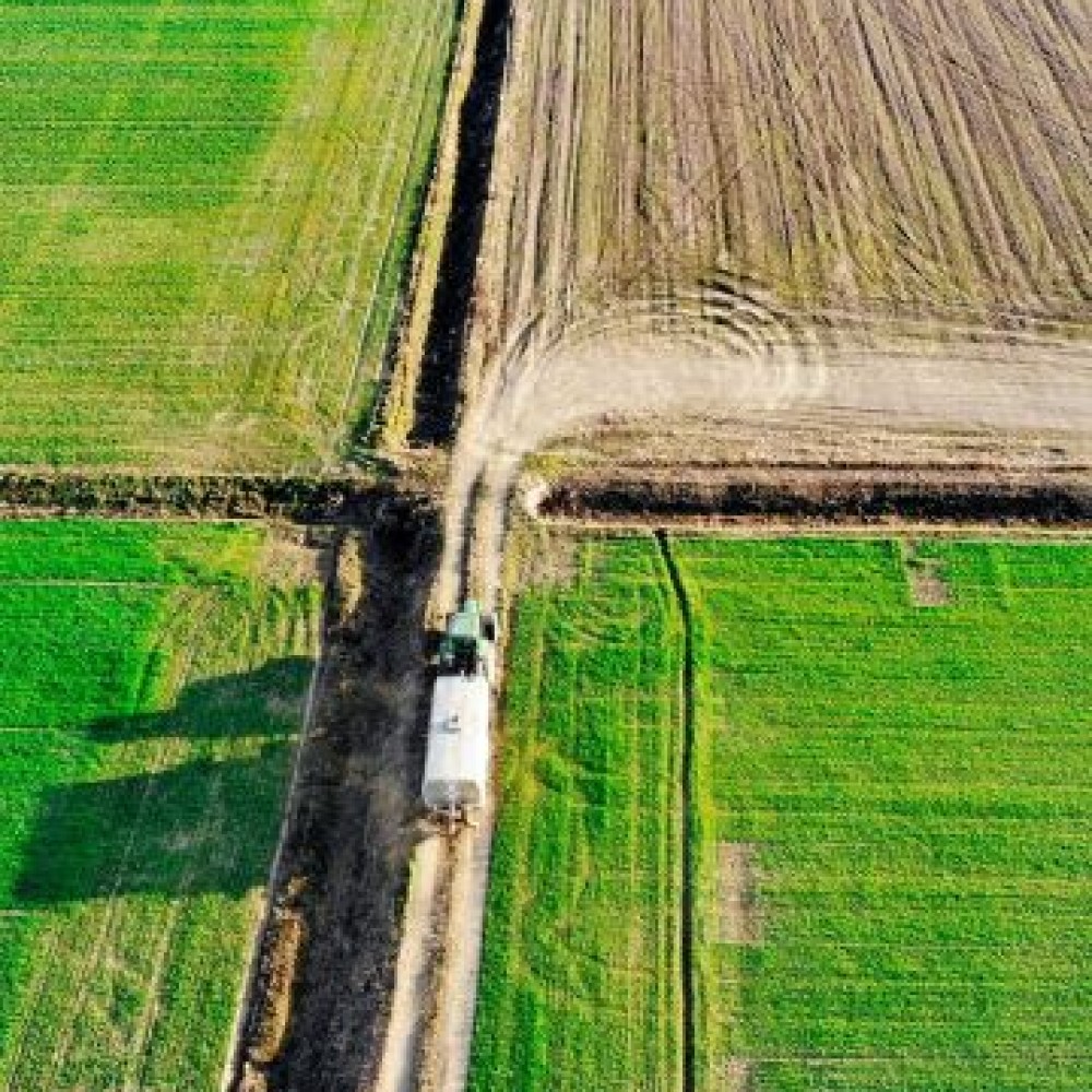 Luchtfoto van tractor met aanhanger die over landbouwgrond rijdt