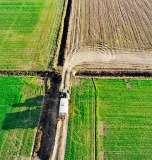 Luchtfoto van tractor met aanhanger die over landbouwgrond rijdt