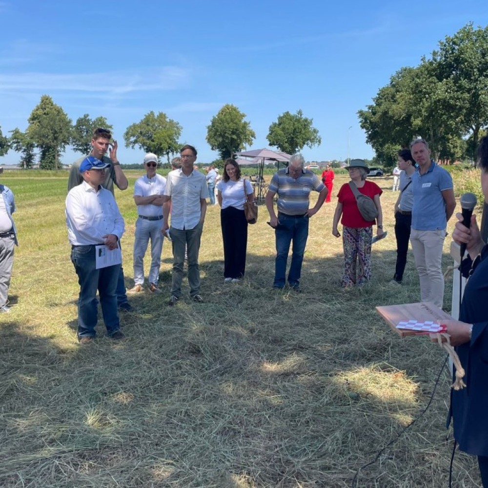 Groepje deelnemers aan het werkbezoek aan De AgroProeftuin de Peel staan in een cirkel rond de dagvoorzitter met een microfoon