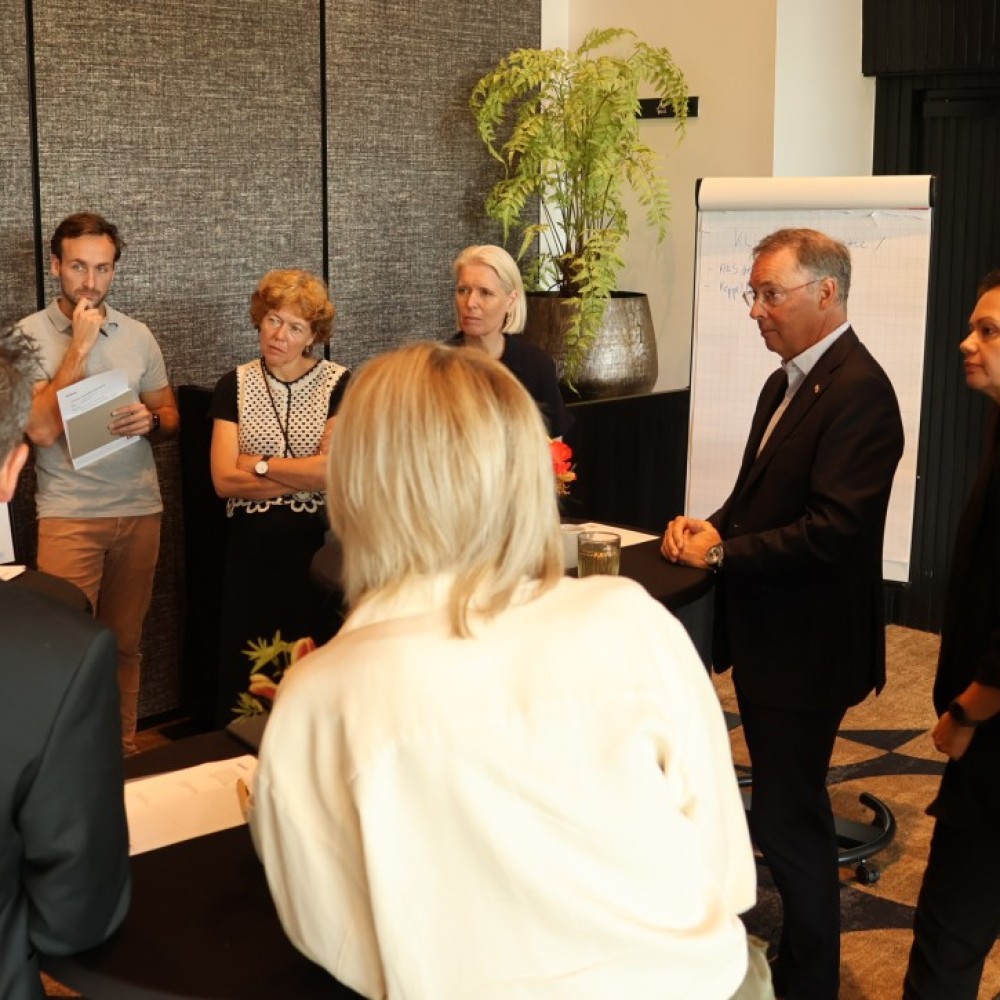 Deelnemers aan de bestuurlijke heidag met elkaar in gesprek rondom een flipover 