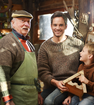 Foto van een blije opa, zoon en kleinzoon in een werkplaats (3 generaties)