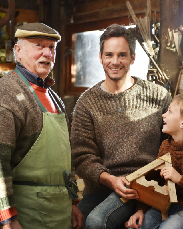 Foto van een blije opa, zoon en kleinzoon in een werkplaats (3 generaties)