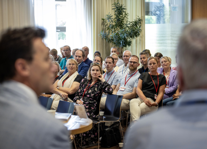 Deelnemers van de bijeenkomst luisteren naar René Peerenboom en Johan Postma in het panel