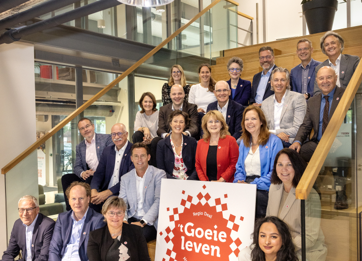 Alle eerste Regio Deal ambassadeurs zitten op een trap rondom een grote afbeelding van het Regio Deal logo 
