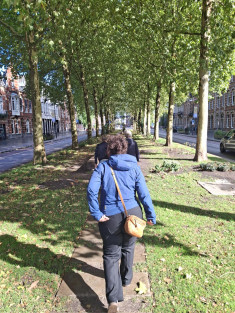 Groep mensen die over een met bomen omzoomd voetpad loopt tussen twee straten in het centrum van Den Bosch