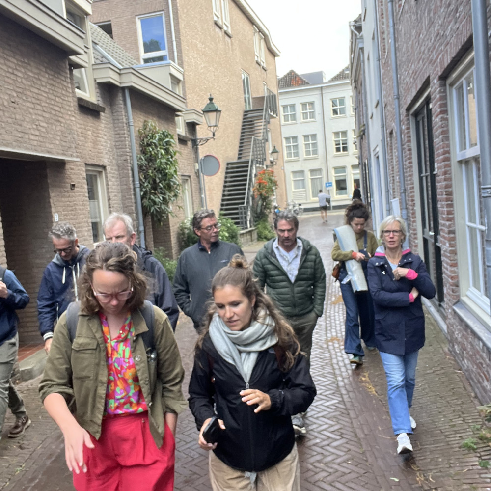 Groep mensen loopt door een straat in het centrum van Den Bosch met oude huizen en veel stenen, weinig groen