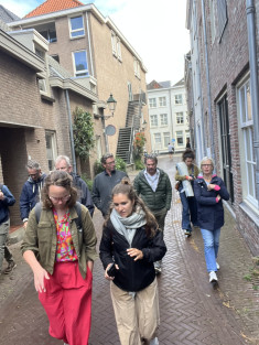 Groep mensen loopt door een straat in het centrum van Den Bosch met oude huizen en veel stenen, weinig groen