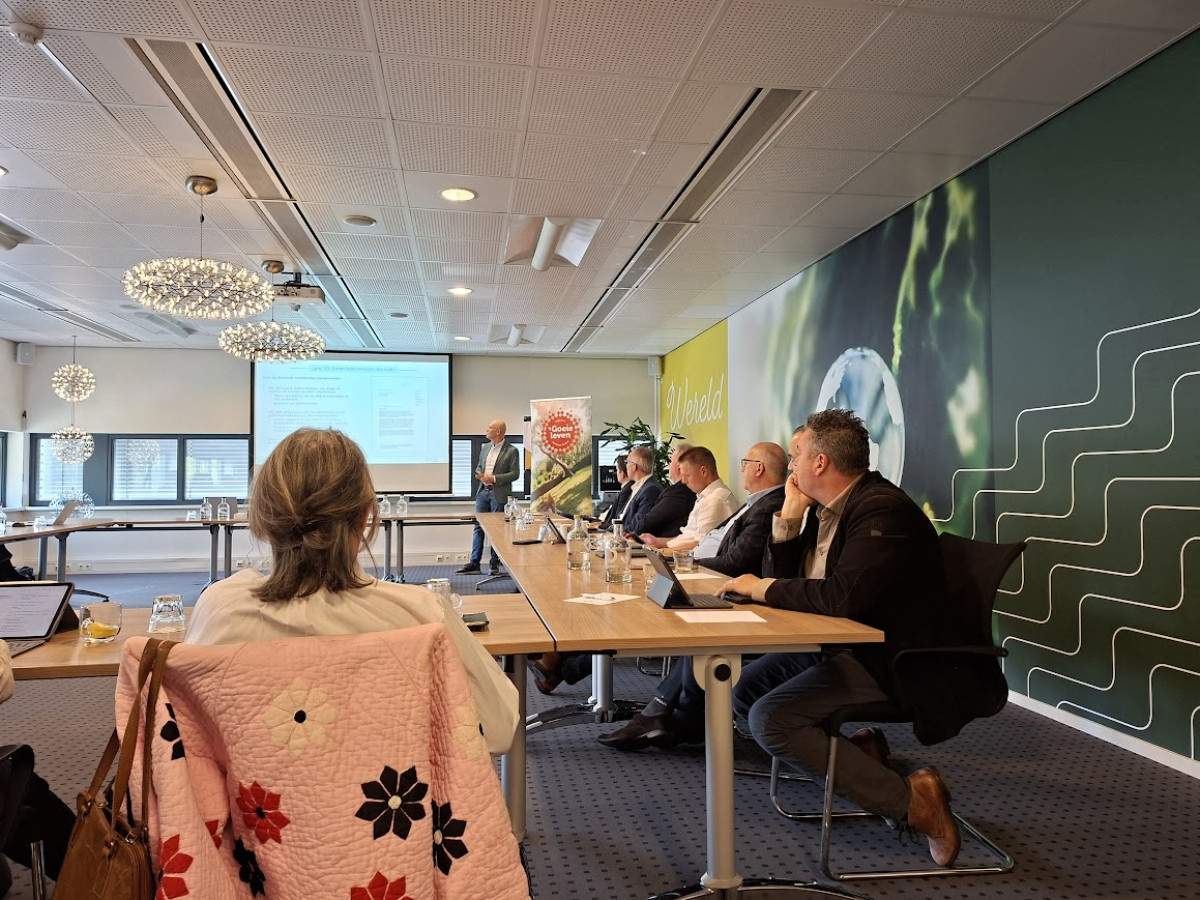 Kees van Geffen geeft bij een scherm een presentatie over netcongestie aan bestuurders die aan tafel zitten in een zaal
