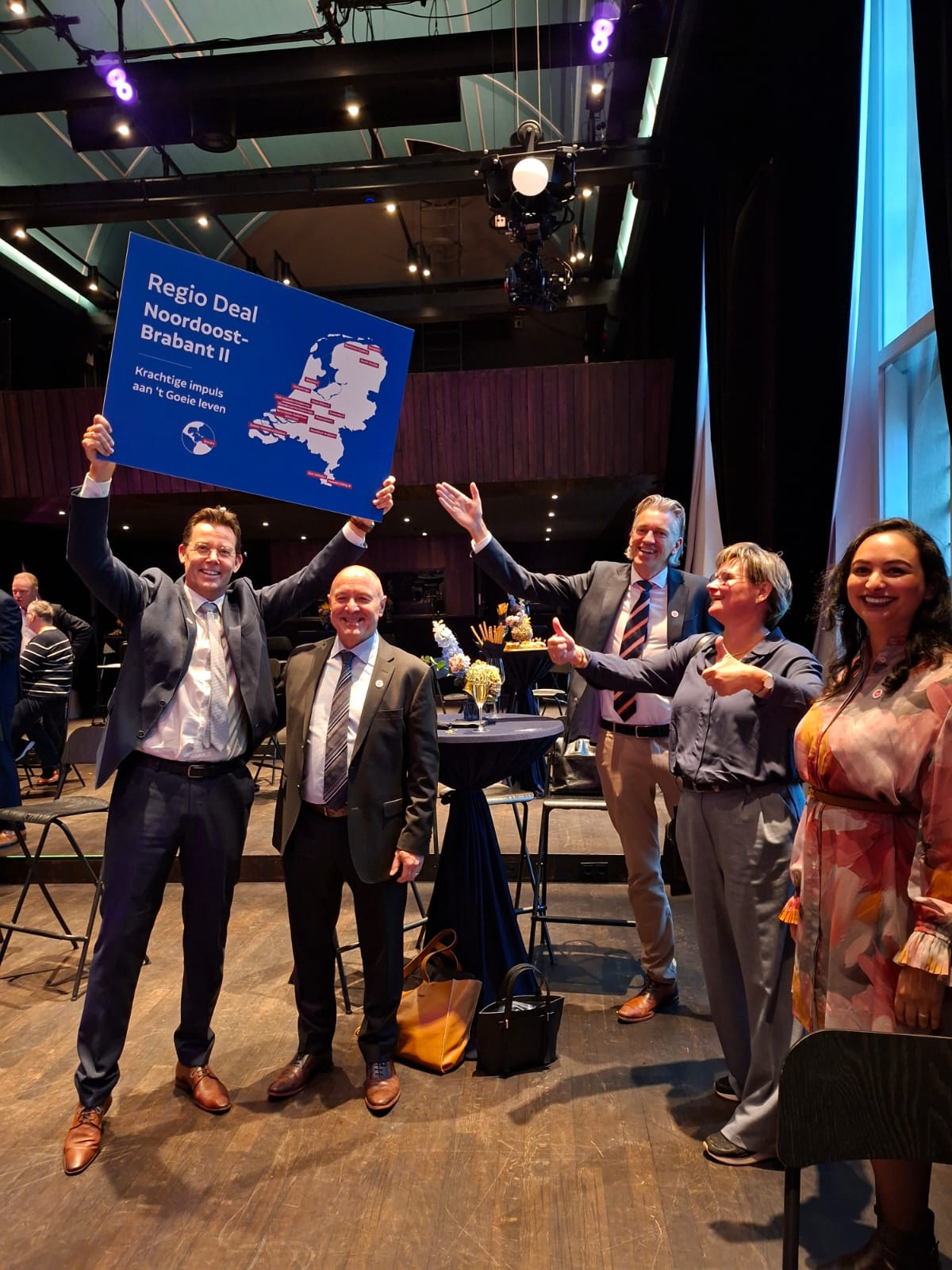 Kleine groep blije mensen waarvan één persoon een bord van Regio Deal 't Goeie leven omhoog houdt 