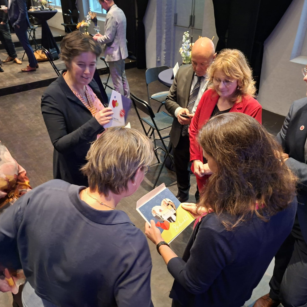 Kleine groep mensen die tijdens een bijeenkomst met elkaar in gesprek is terwijl ze kaarten bekijken.