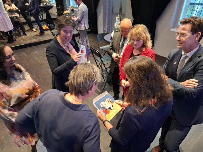 Kleine groep mensen die tijdens een bijeenkomst met elkaar in gesprek is terwijl ze kaarten bekijken.