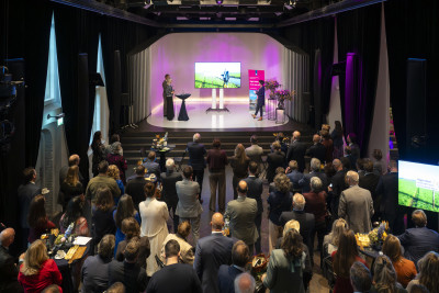 Grote groep aanwezigen die naar een presentatie kijkt op een podium tijdens de officiële Regio Deal bijeenkomst