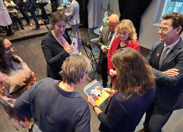 Kleine groep mensen die tijdens een bijeenkomst met elkaar in gesprek is terwijl ze kaarten bekijken.