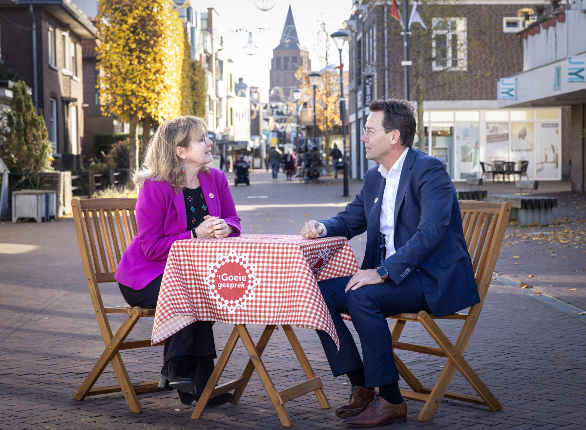 Marieke Moorman en René Peerenboom zitten aan een klein bistrostafeltje met een Brabants kleedje midden in een winkelstraat 