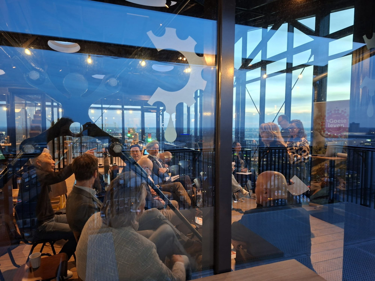 Programmamanagers, projectleiders en bestuurders van de Regio Deal met elkaar in gesprek in een glazen ruimte bij The Chocolate Factory met uitzicht over de stad.