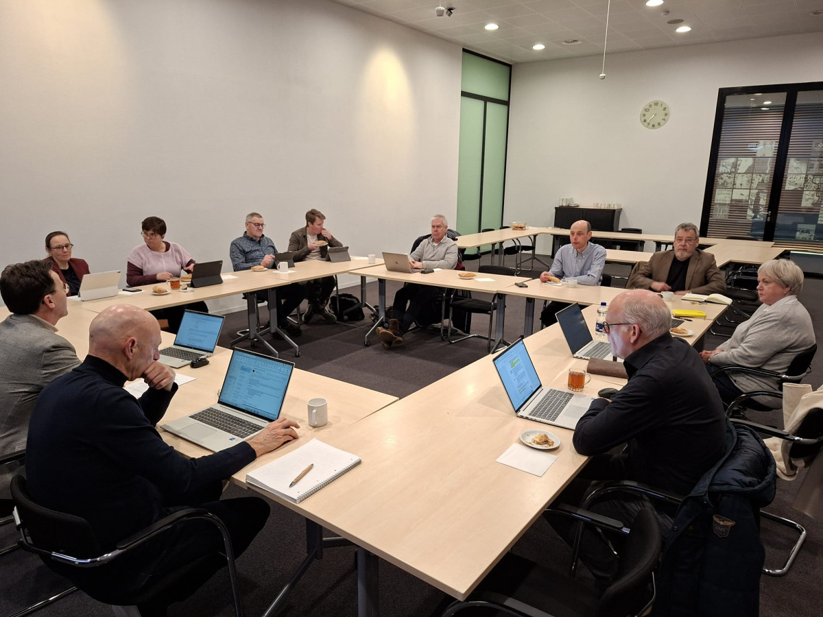 Vergadering van de klankbordgroep raadsleden rond een U‑vormige tafel waar deelnemers met laptops overleggen.