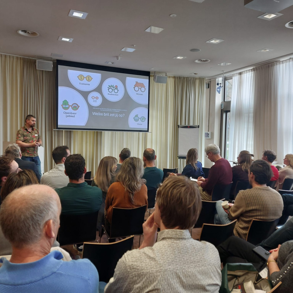 Presentatie over bodem- en watersturing voor een groep aanwezigen in een conferentieruimte.