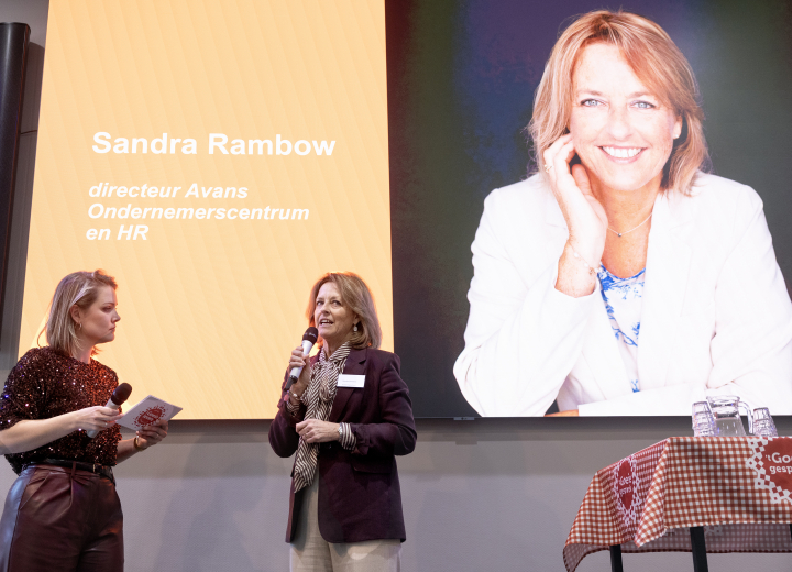 Spreker op podium naast dagvoorzitter tijdens evenement met presentatie ‘Sandra Rambow – Avans Ondernemerscentrum en HR’