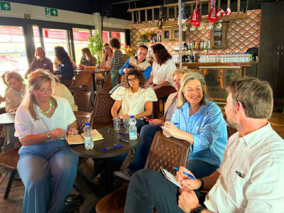 Deelnemers aan de regionale loopbaandag van Noordoost Brabant Werkt met elkaar in gesprek aan tafel met andere deelnemers op de achtergrond.