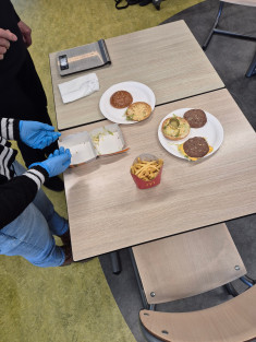 Leerlingen analyseren een hamburger en frietjes tijdens praktijkles voeding.