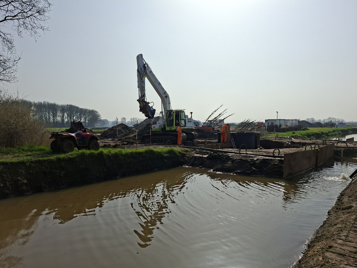 Uitvoering van beekherstelwerkzaamheden door een kraan aan de oevers van een rivier 