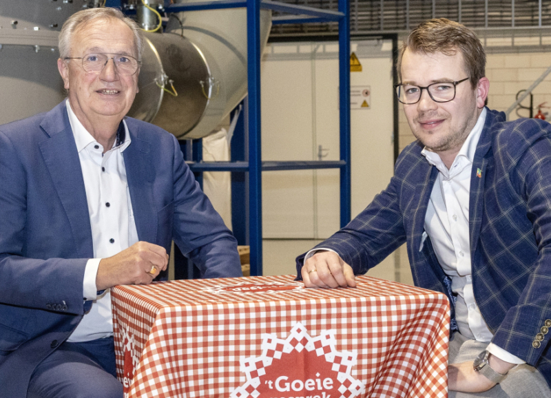 Jan Gijaarts en Henk Jan de Kat voeren overleg aan een tafel in een industriële omgeving met een rood-wit kleedje over samenwerking en innovatie in voedselverspilling.
