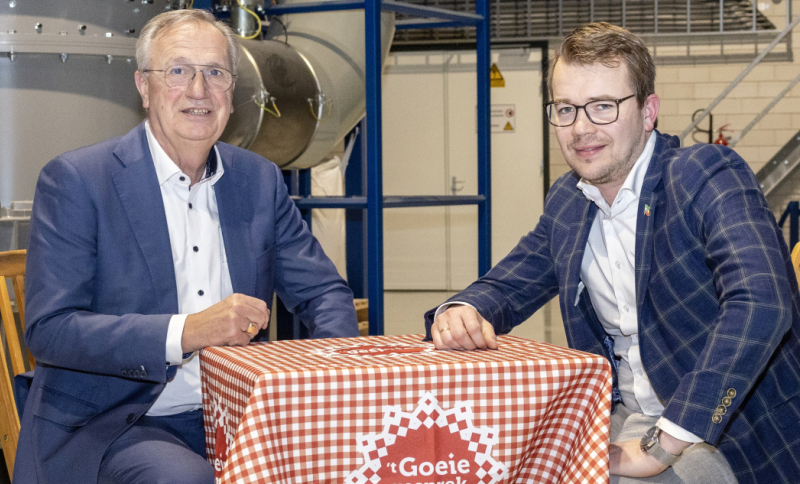 Jan Gijaarts en Henk Jan de Kat voeren overleg aan een tafel in een industriële omgeving met een rood-wit kleedje over samenwerking en innovatie in voedselverspilling.