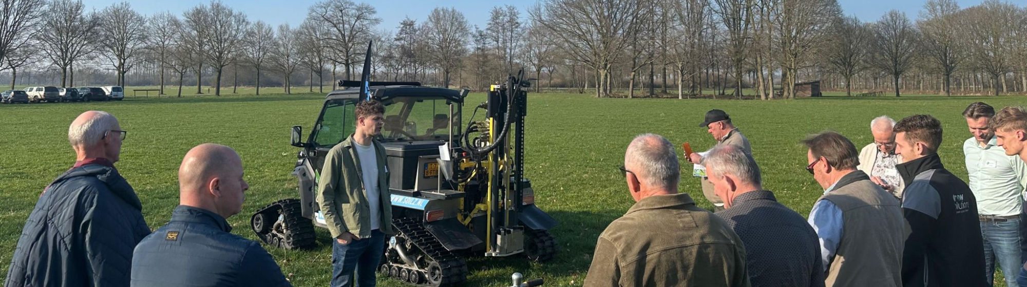 Demonstratie van een landbouwmachine aan groep aanwezigen boeren op landbouwgrond.