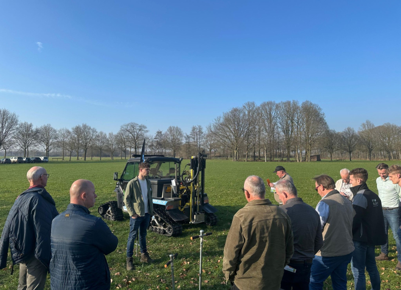 Demonstratie van een landbouwmachine aan groep aanwezigen boeren op landbouwgrond.