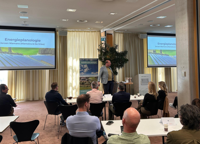 Presentatie over zonne-energie en energietransitie met spreker en deelnemers tijdens workshop met slides van zonnepaneleninstallaties.