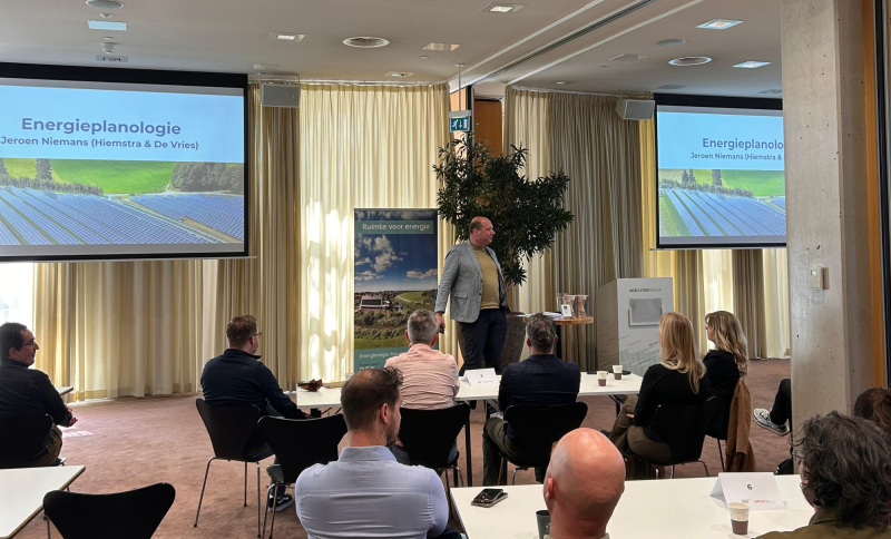 Presentatie over zonne-energie en energietransitie met spreker en deelnemers tijdens workshop met slides van zonnepaneleninstallaties.