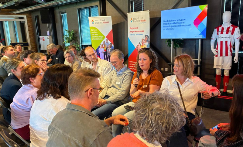 Deelnemers aan de regionale loopbaandag van Noordoost Brabant Werkt met elkaar in gesprek in twee rijen zittend tegenover elkaar.