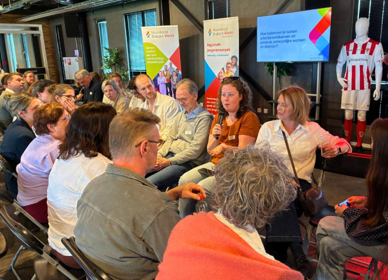 Deelnemers aan de regionale loopbaandag van Noordoost Brabant Werkt met elkaar in gesprek in twee rijen zittend tegenover elkaar.
