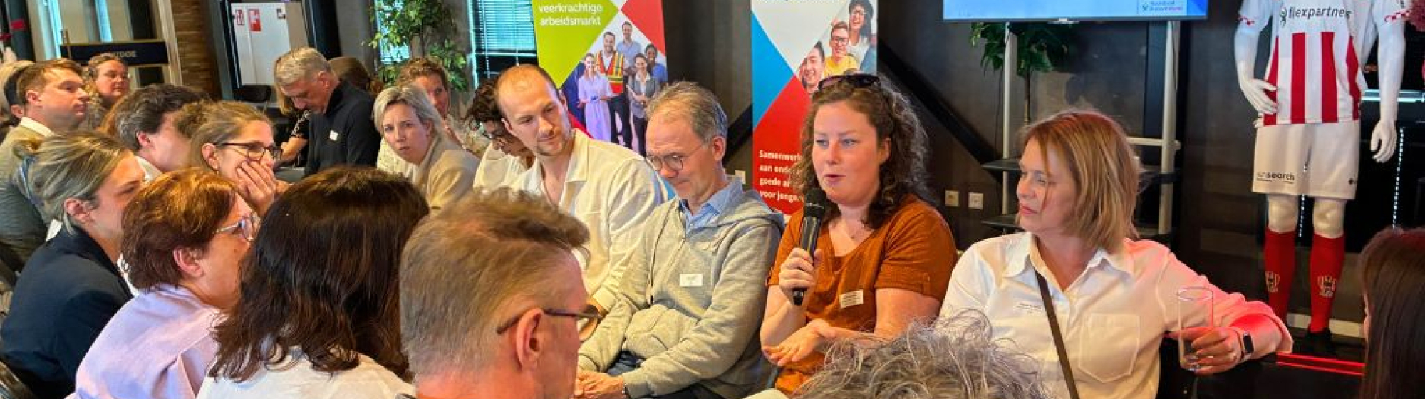Deelnemers aan de regionale loopbaandag van Noordoost Brabant Werkt met elkaar in gesprek in twee rijen zittend tegenover elkaar.
