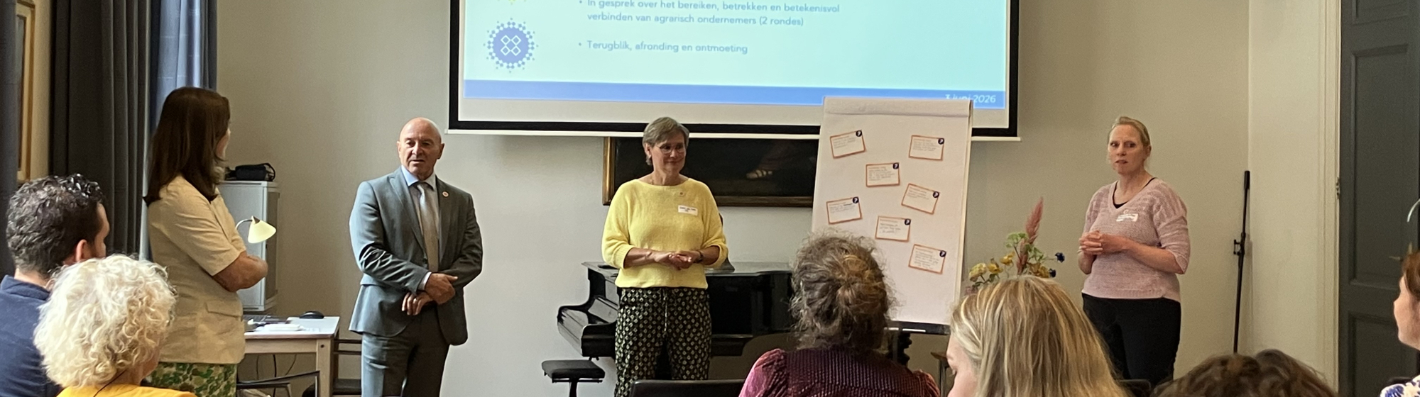 Presentatie door dre personen met groot scherm tijdens crossoverbijeenkomst over agrarisch ondernemerschap voor de deelnemers en flip-over
